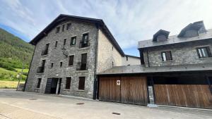 ein großes Steingebäude mit einer Holzgarage in der Unterkunft Rincon de Pepo in Villanúa