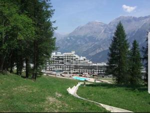 a park with a large building in the mountains at Appartement sur le Parc des Ecrins in Puy-Saint-Vincent