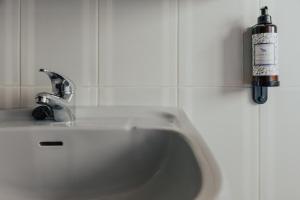 a white sink in a bathroom with a bottle on the wall at Torreira Beach Apartment in Torreira +29 photos