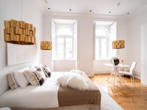 a white bedroom with a large bed and a table at Akicity Santarém Gemstone in Santarém