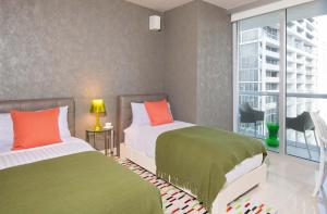 a bedroom with two beds with green and orange pillows at MVR - Oceanfront Corner Balcony Luxe SPA in Miami