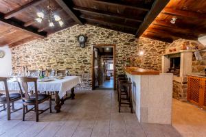 a dining room with a table and a stone wall at Lagar de Beuvas in Camanzo