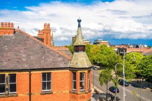 an old brick building with a tower on a street at Elysée Suites - Chic 1 Bed Flat in Southport in Southport