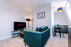 a living room with a blue couch and a tv at Elysée Suites - Chic 1 Bed Flat in Southport in Southport