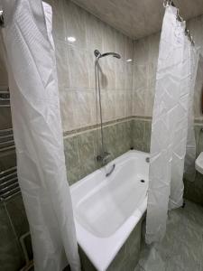 a bath tub with a shower curtain in a bathroom at Duplex Apartment near Nizami street in Mekhrably +15 photos
