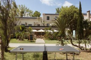 a ping pong table in front of a building at Hôtel les jardins du canal - solaire eco reponsable - piscine chauffée - parking - garage - bornes électriques - accueil vélos - kids friendly in Aigues-Mortes