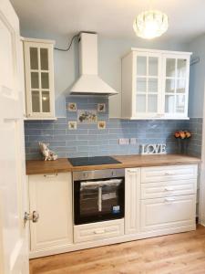 a kitchen with white cabinets and a stove top oven at 10 Seconds to Main Street! in Wexford