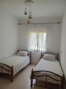 two beds in a room with a window at L'Olivier à Marina Golf Vue sur Piscine, Wi-Fi et Clim in Asilah +14 photos