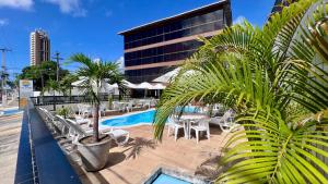a resort with a pool and chairs and a building at Las Brisas Beach Hotel in Natal