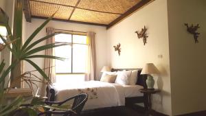 um quarto com uma cama, uma janela e uma planta em Villa Mungkala em Bangkok