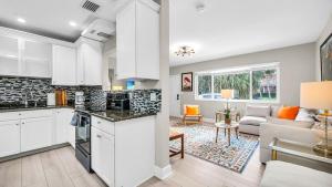 a kitchen with white cabinets and a living room at Casa Chic El Cid in West Palm Beach