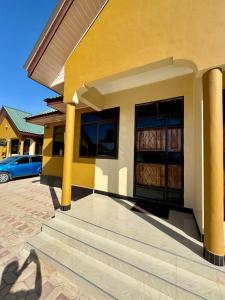 un edificio amarillo con una escalera delante en Watra Apartments, en Dodoma