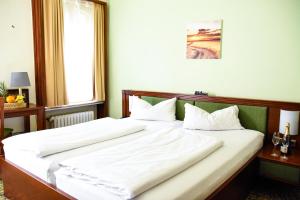 a bedroom with a large bed with white sheets at Parkhotel Zirndorf in Zirndorf