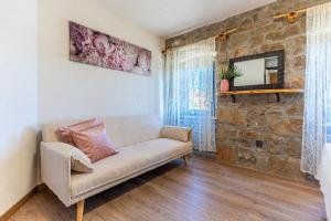 Una sala de estar con un sofá y una pared de piedra. en Villa Amarie, en Štivan