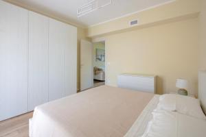 a white bedroom with a bed and a bathroom at Pellicano Suite Apartment in Marina di Grosseto +16 photos