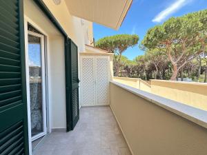 a balcony with a green door and trees at Pellicano Suite Apartment in Marina di Grosseto