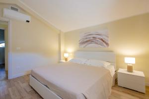 a bedroom with a large white bed and two lamps at Pellicano Suite Apartment in Marina di Grosseto