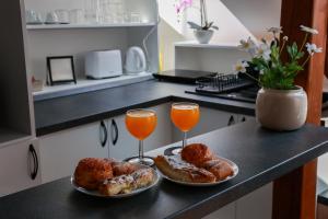 two plates of donuts and two glasses of orange juice at Heroes Apartment Esztergom in Esztergom +6 photos
