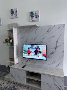 a flat screen tv sitting on a white marble wall at Rumah Melur - 10km dari Matrik Kelantan in Pasir Puteh