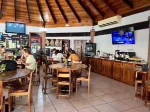 a group of people sitting at tables in a restaurant at Hotel Villa Acacia in Playa Hermosa