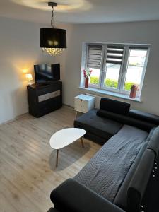 a living room with a black couch and a tv at Apartament u Magdy in Giżycko
