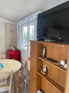 ein Wohnzimmer mit einem großen Flachbild-TV auf einem hölzernen Entertainment-Center in der Unterkunft Location Mobil-home - Vacances près de la mer in Carnac
