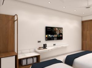 a bedroom with a tv on a white wall at Radha Ratna Hotel in Ayodhya