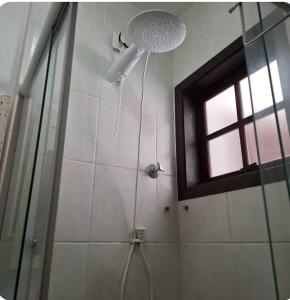 a shower with a shower head and a window at Refúgio Azul na Praia - Itaipuaçu-RJ in Maricá