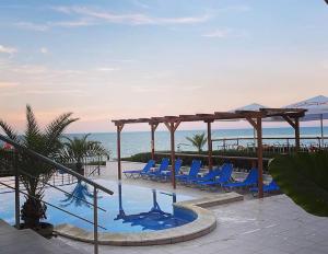 a swimming pool with blue lounge chairs next to the ocean at Byala Vista A-54 in Byala