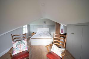 a attic room with a bed and two chairs at The Swilly Suite in Castlequarter