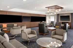 a waiting room with couches and chairs and televisions at Courtyard Cleveland Airport South in Middleburg Heights