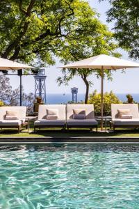 a pool with chairs and umbrellas next to the water at Hotel Miramar Barcelona GL in Barcelona