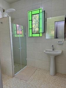 a bathroom with a shower and a sink and a window at Chalé das Margaridas em São Lourenço a 2km do Parque das Águas in São Lourenço
