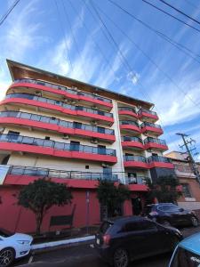 a tall building with cars parked in front of it at Dpto a pasos de la playa San José in Encarnación