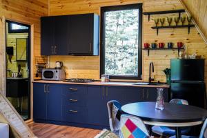 une cuisine avec des armoires bleues et une table dans une cabine dans l'établissement Kokhta Cottage Kazbegi 2, à Kazbegi 38 autres photos