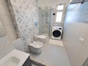 a white bathroom with a toilet and a sink at Almarè House in Giardini Naxos