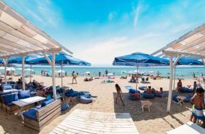 a group of people on a beach with blue umbrellas at Sveti Vlas Fort Noks Panorama SAS in Sveti Vlas