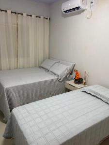 two beds in a small room with a window at casa de veraneio jalapão in São Félix do Tocantins