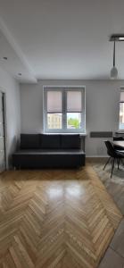 a living room with a black couch and two windows at Centrum Lipowa 16 Apartamenty LUNA Bialystok in Białystok
