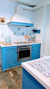 a blue kitchen with a stove and a sink at Stellinas House 2 in Andros