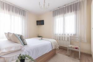 a white bedroom with a bed and a tv at Mi casita del norte a 150 m de la playa in Mogro