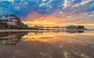 een uitzicht op een strand met een pier bij zonsondergang bij The Hide Away in Cromer