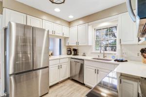 a kitchen with white cabinets and a stainless steel refrigerator at 1 Block to Ocean Fun in Hilton Head Island +48 photos