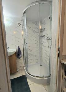 a shower with a glass door in a bathroom at Pod Lasem Kwatery Pracownicze in Gollnow