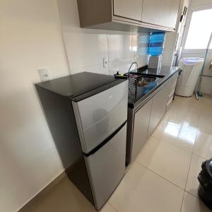 een kleine keuken met een spoelbak en een koelkast bij Apto Novo com Ar e Wi-Fi Perto da UFU Monte Carmelo in Monte Carmelo