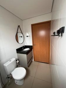a bathroom with a toilet and a wooden door at Apto Novo com Ar e Wi-Fi Perto da UFU Monte Carmelo in Monte Carmelo +16 photos