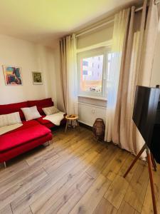 a living room with a red couch and a window at Modern Loft Basel Airport ArtBasel in Saint-Louis