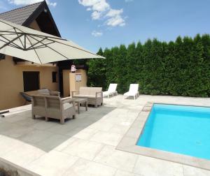 a patio with chairs and an umbrella and a pool at Natural Cottage Una in Bihać