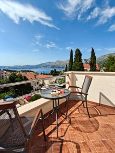 eine Terrasse mit zwei Stühlen und einem Tisch auf einem Balkon in der Unterkunft Apartments Miljas in Cavtat