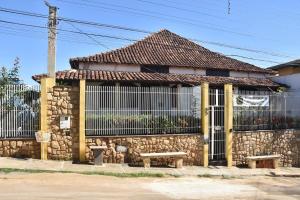 a stone building with a bench and a fence at Pousada Colonial in Cachoeiro de Itapemirim